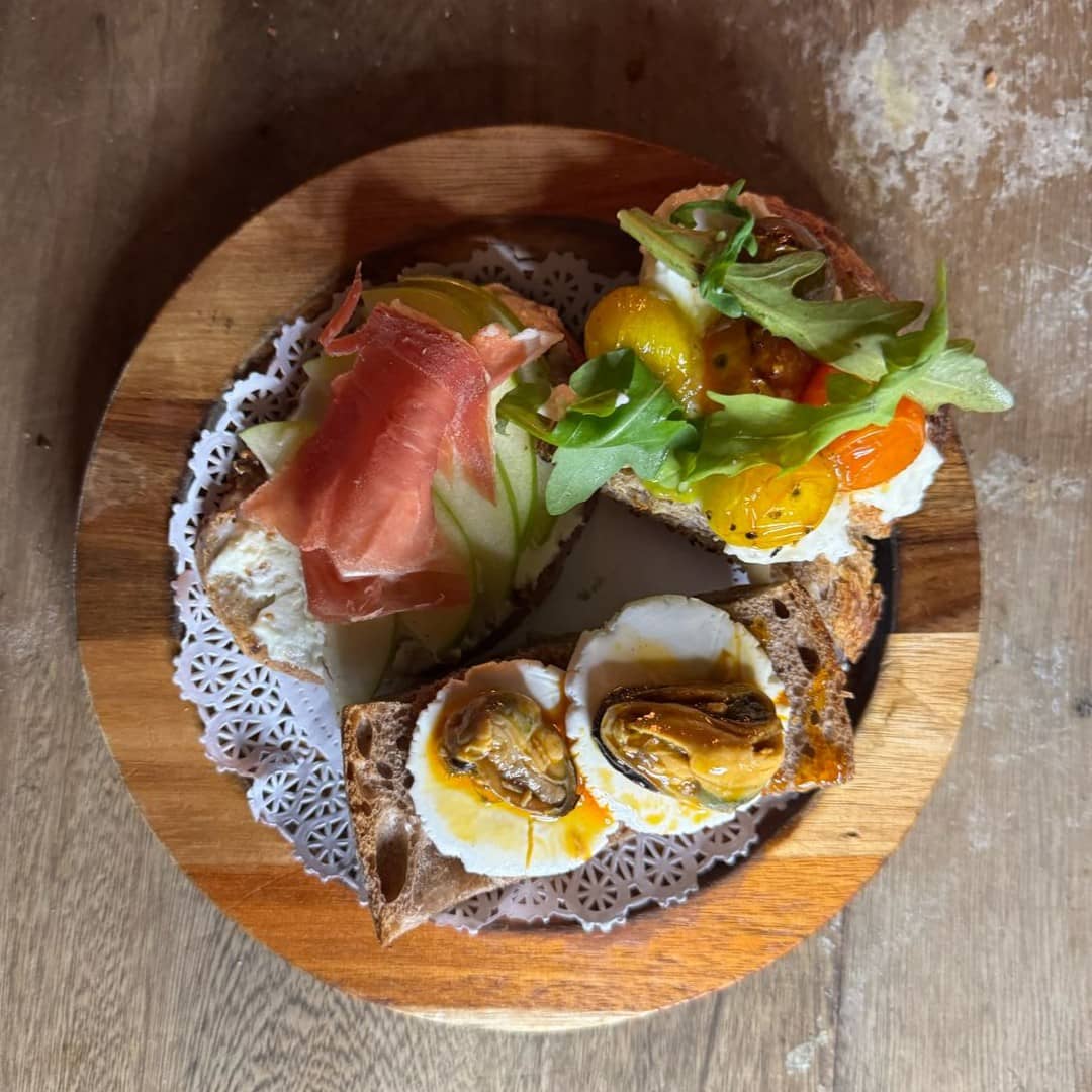 Plato gourmet de vegetales en torre acompañado de una bebida.
