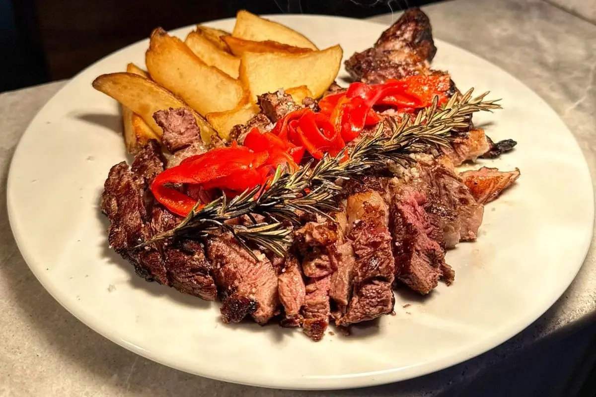 Plato con filete de res a la parrilla, papas gajo y pimientos asados con romero.