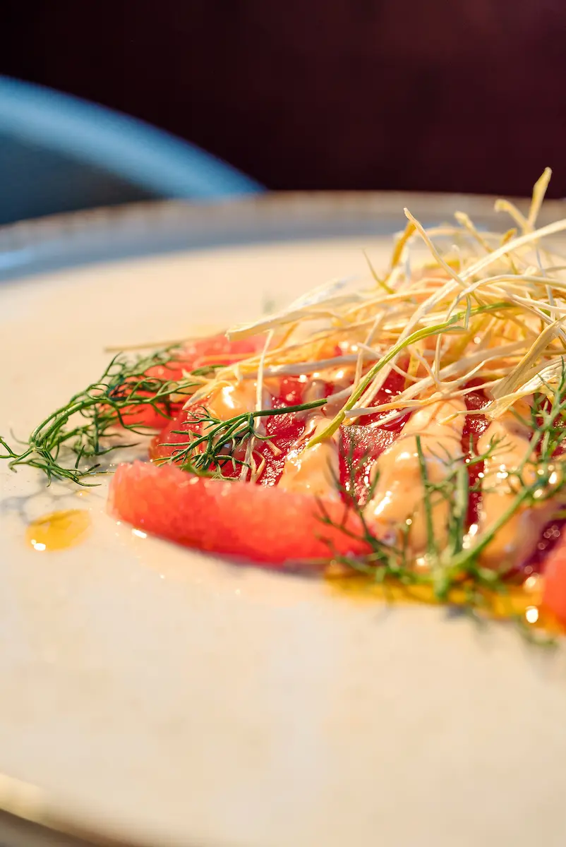 Plato gourmet con pescado fresco y guarnición de hierbas finas.