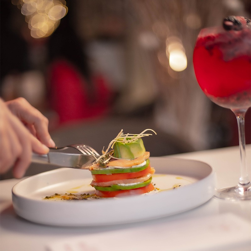 Platillo gourmet con tomate, pepino, salmón y brotes, acompañado con una bebida